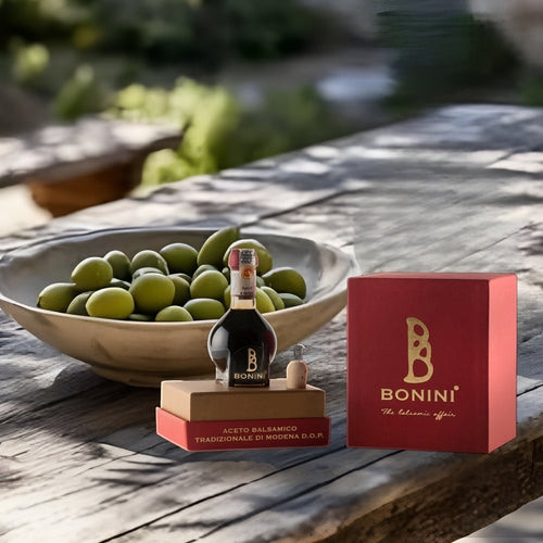 Aceto Balsamico Tradizionale di Modena DOP 12 ans, coffret rouge Bonini, sur une table en bois sous les oliviers